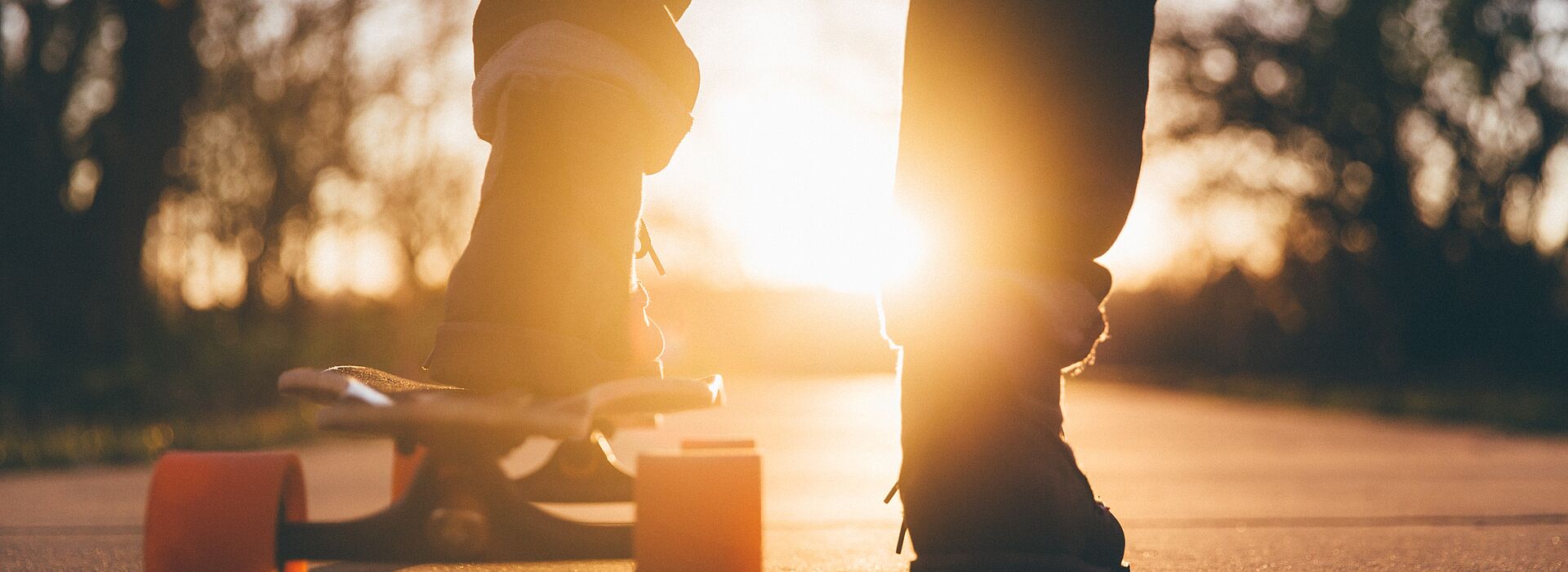 Füße am Skateboard im Gegenlicht