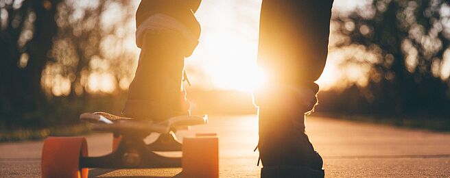 Füße am Skateboard im Gegenlicht