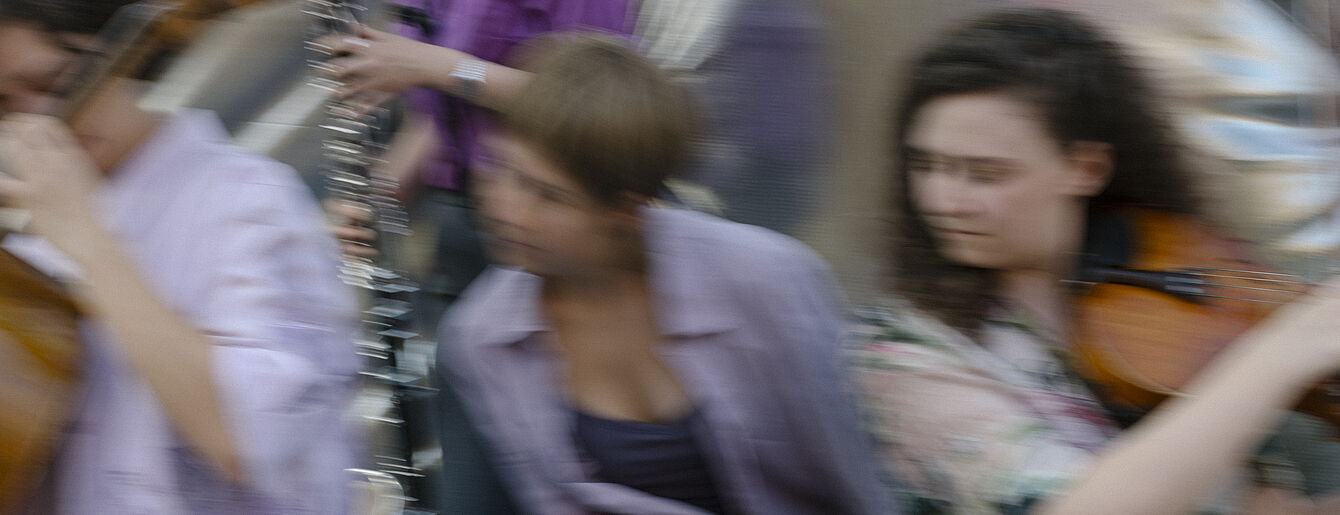 Unscharfe Aufnahme von mehreren Personen, die Musikinstrumente spielen.