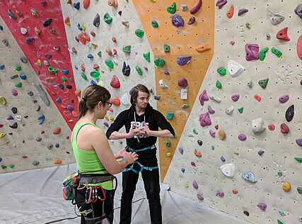 Zwei Personen vor der Kletterwand in der Kletterhalle 