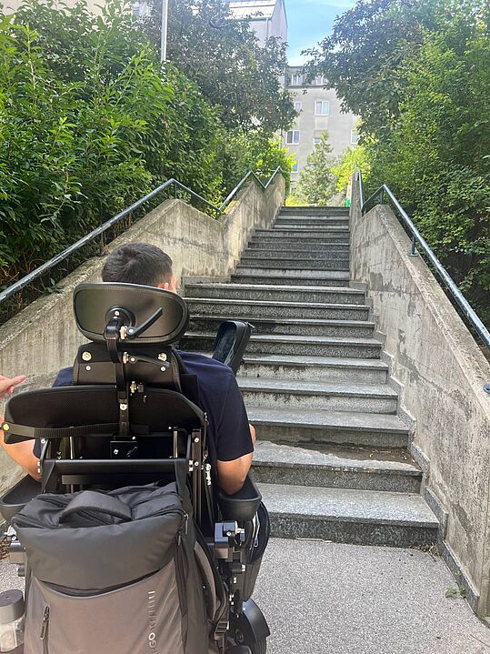 Foto: © Karlo Palavra Person im Rollstuhl vor einer langen Treppe mit Geländern auf beiden Seiten