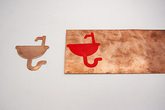 Kupferplatte und ausgeschnittenes Waschbecken-Piktogramm aus Kupferplatte
