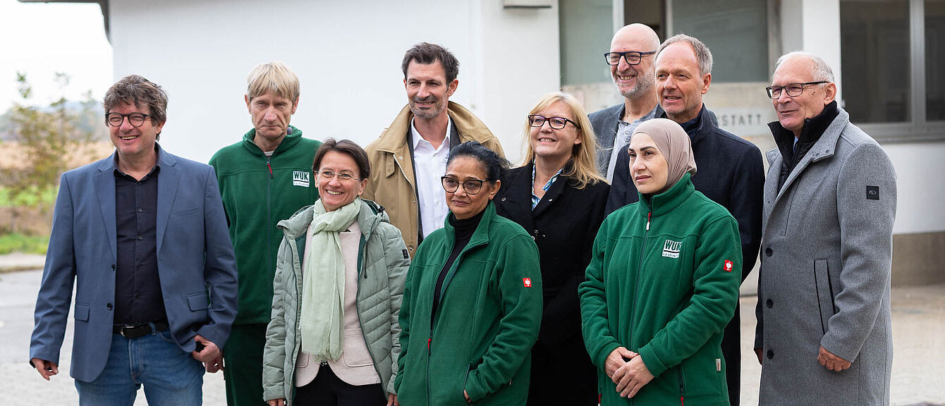 Gruppe von zehn Personen vor einem Gebäude mit weißer Fassade